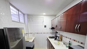 Une cuisine moderne dotée d’appareils électroménagers en acier inoxydable, d’un revêtement mural en carreaux blancs et de meubles de rangement en bois.