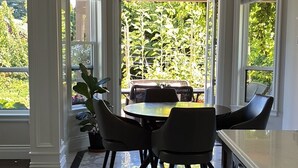 Een moderne keuken met een marmeren vloer, een eethoek met een tafel en stoelen, en grote ramen met uitzicht op de tuin.