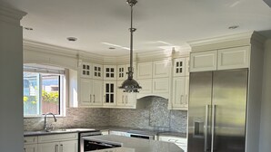 Een moderne keuken met witte kasten, een grote roestvrijstalen koelkast en een marmeren vloer.
