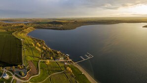 An aerial view of a coastal area with a large body of water, a marina, and surrounding fields. - Holiday Home Concordia by the Lake with Covered Terrace and Air Conditioning (Seeland)