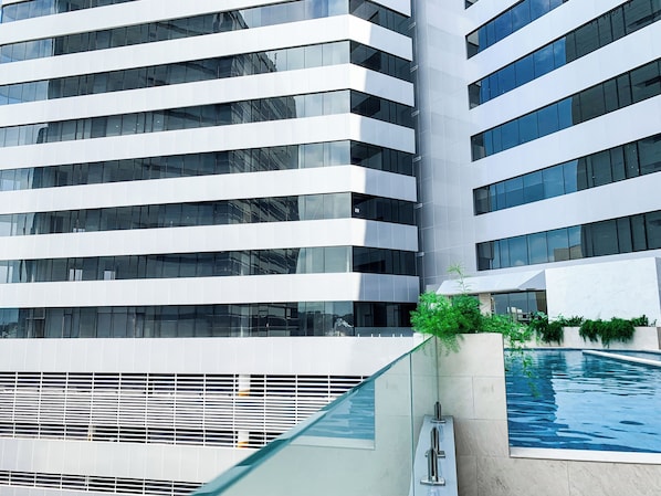 A modern building with a glass facade and a pool area.