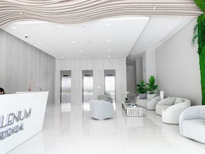 A modern reception area with a marble floor, white sofas, and a reception desk.