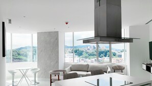 Eine moderne Küche mit Kochinsel, großen Fenstern und Stadtblick, im minimalistischen Stil gehalten.
