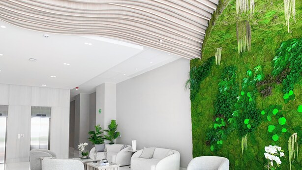 Eine moderne Lobby mit weißen Möbeln, einer Wand aus Moos und einer Decke mit wellenförmigem Design.
