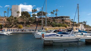 A marina with boats docked, a large cylindrical structure, and a building on a hillside. - Modern apartment with jacuzzi Los Altos - Orihuela Costa (Torrevieja)