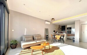 Ein modernes Wohnzimmer mit Sofa, Couchtisch und Essbereich.