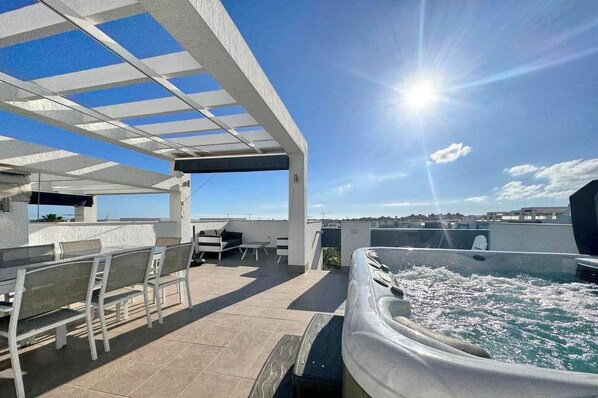 Eine Dachterrasse mit Whirlpool, Sitzgelegenheiten im Freien und freiem Blick auf die Stadtlandschaft.