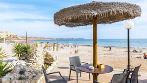A beachside patio with a thatched umbrella, wicker chairs, and a table. - Modern apartment with jacuzzi Los Altos - Orihuela Costa (Torrevieja)