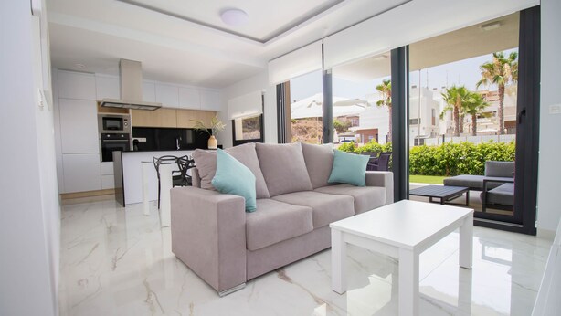 Een moderne woonkamer met een bank, een salontafel en uitzicht op het terras.