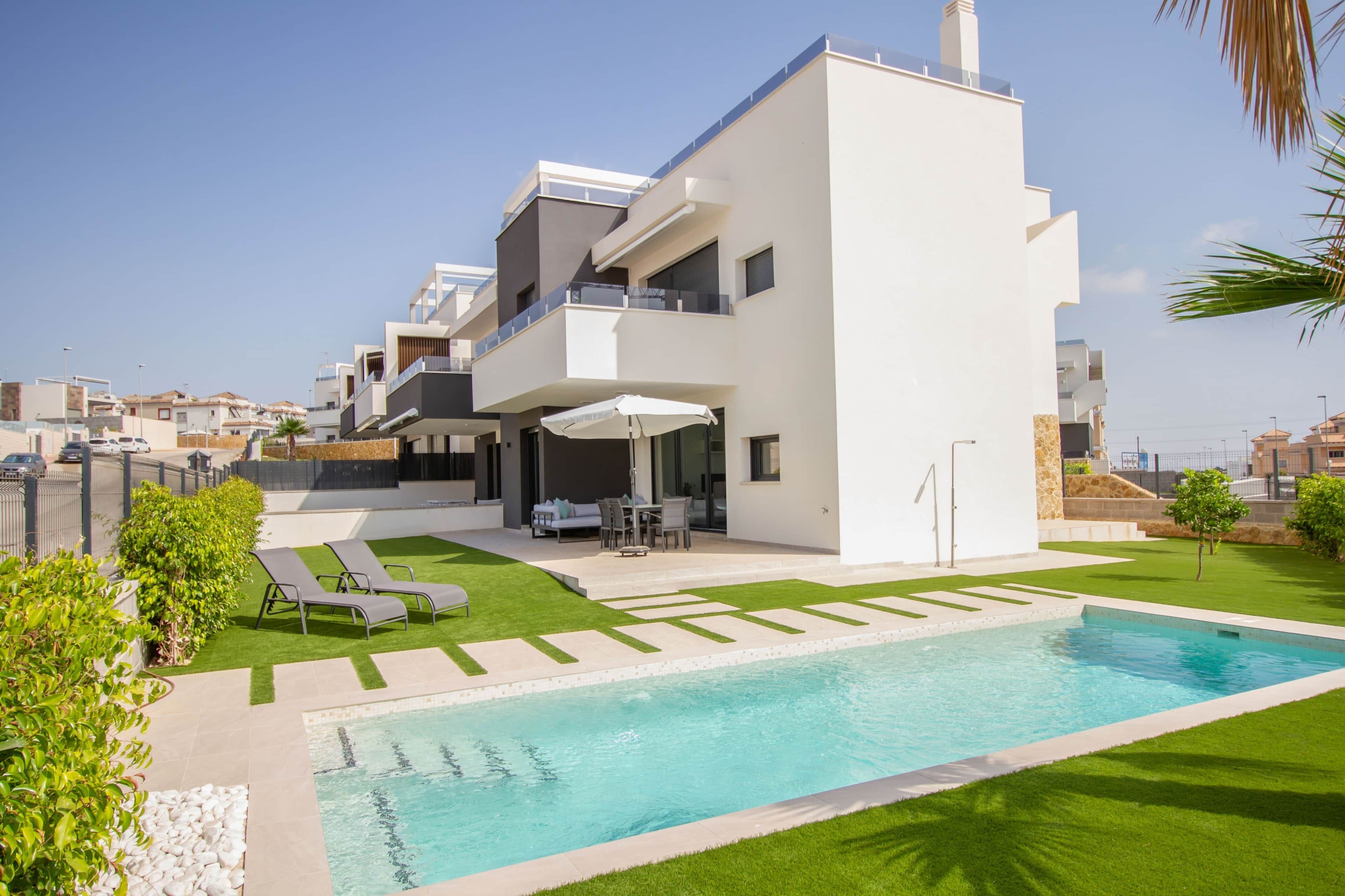 Ein modernes, mehrgeschossiges Wohngebäude mit Swimmingpool, Sitzgelegenheiten im Freien und einem gepflegten Rasen.