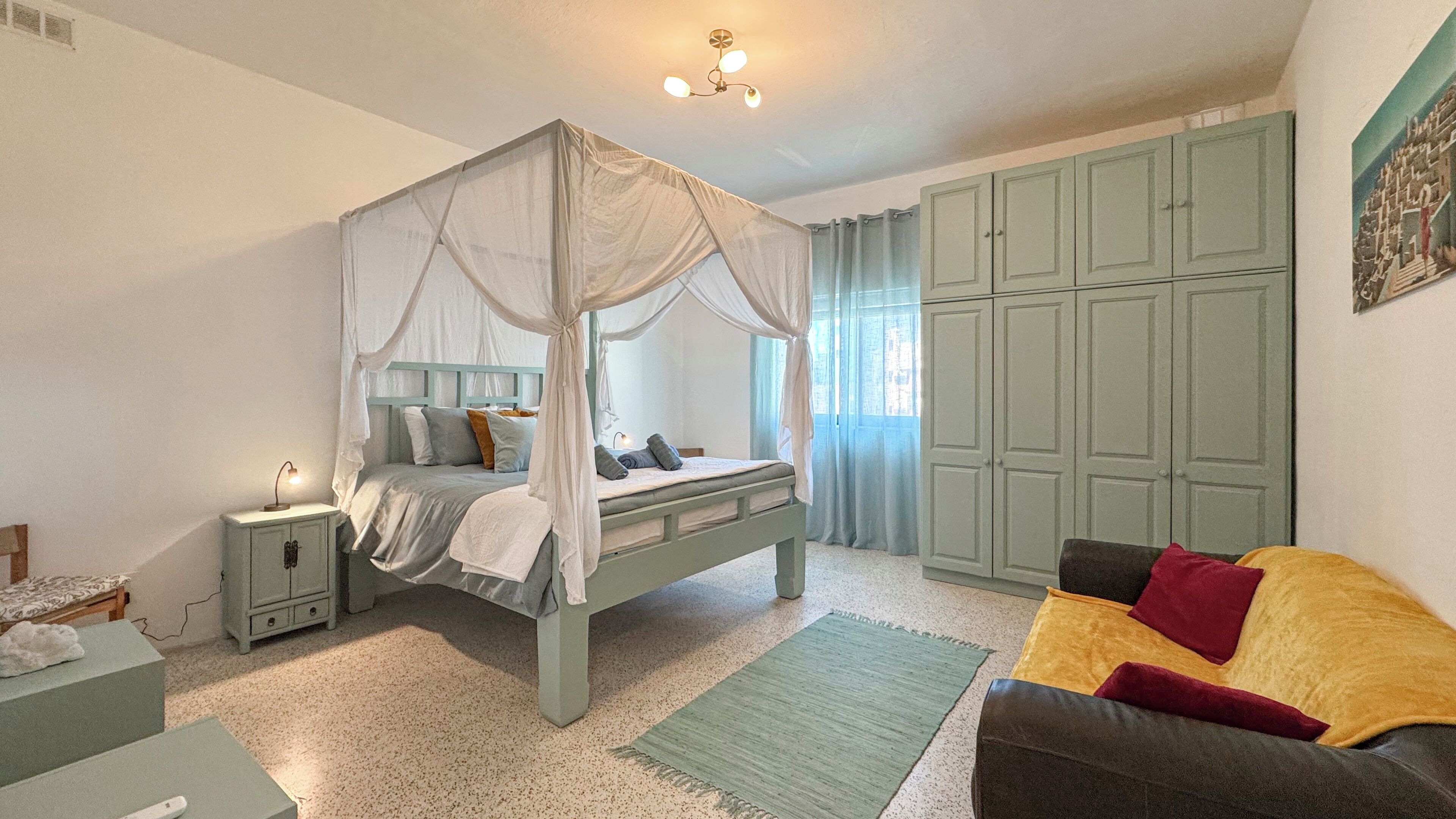 Ein Schlafzimmer mit einem Himmelbett, einem grünen Kleiderschrank, einem Nachttisch, einem grünen Sofa und einem grünen Teppich.