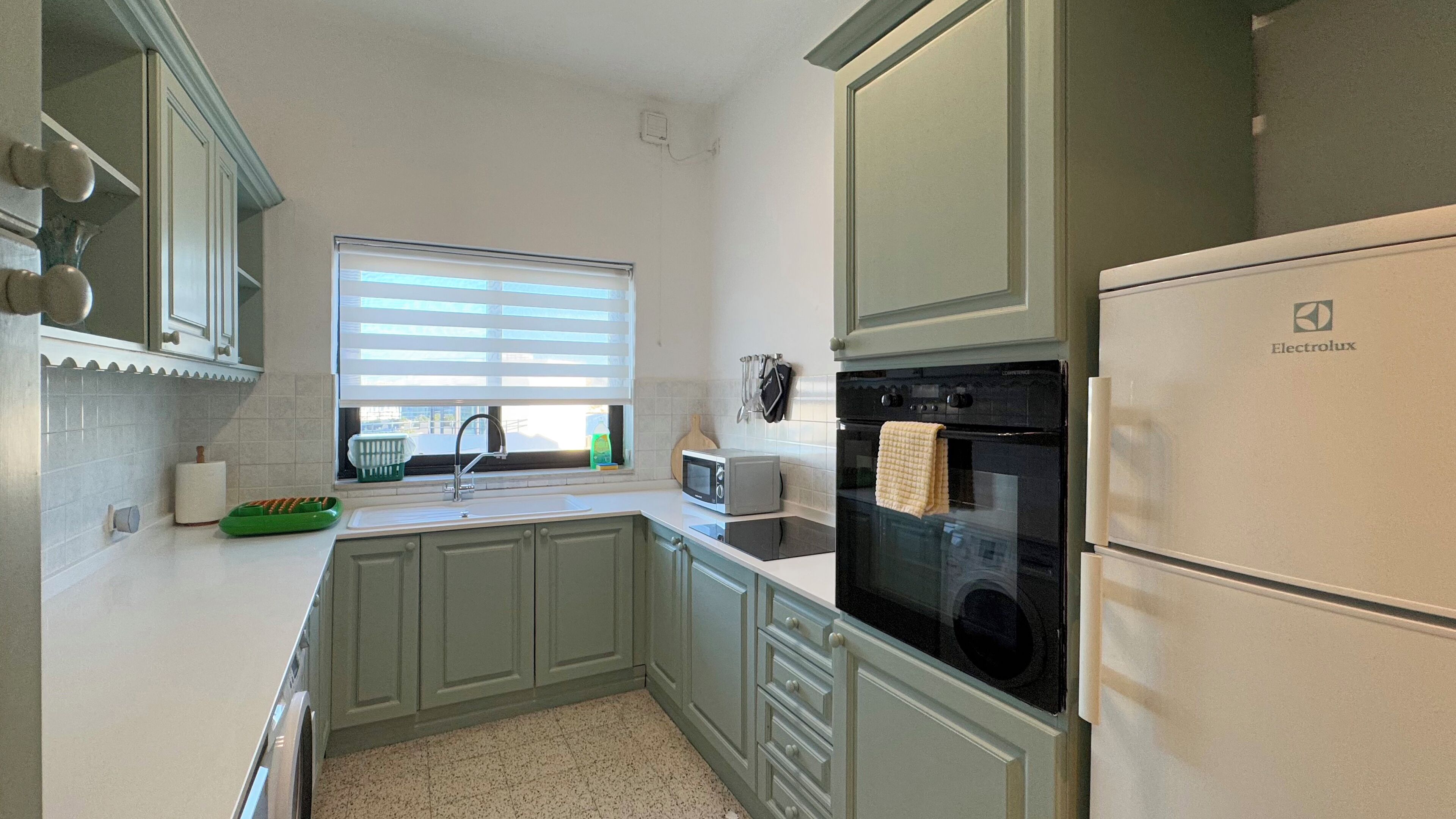 A kitchen with a sink, a microwave, an oven, and a refrigerator.