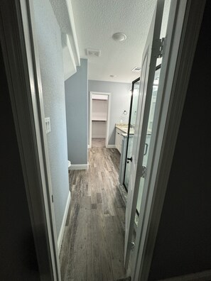 Ein schmaler Flur mit Holzboden, einer Tür zu einem Badezimmer und einem Schrank mit Handtuchhalter.