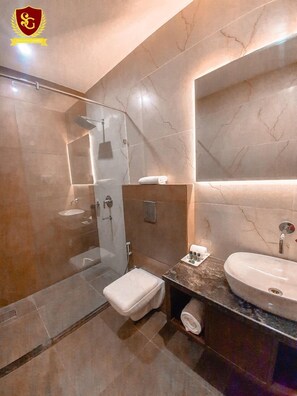 Un baño moderno con ducha acristalada, tocador con lavamanos y un espejo grande.