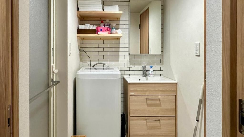 Un bagno compatto con lavatrice, lavabo e mobiletto in legno.