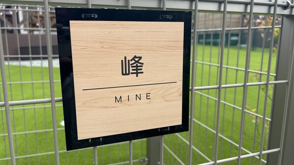 Een houten bord met Chinese karakters en het woord 'MINE' op een metalen hek.