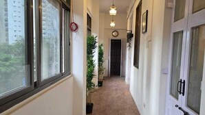 Un couloir étroit avec un plancher en bois, des murs blancs et une porte sur le côté droit.
