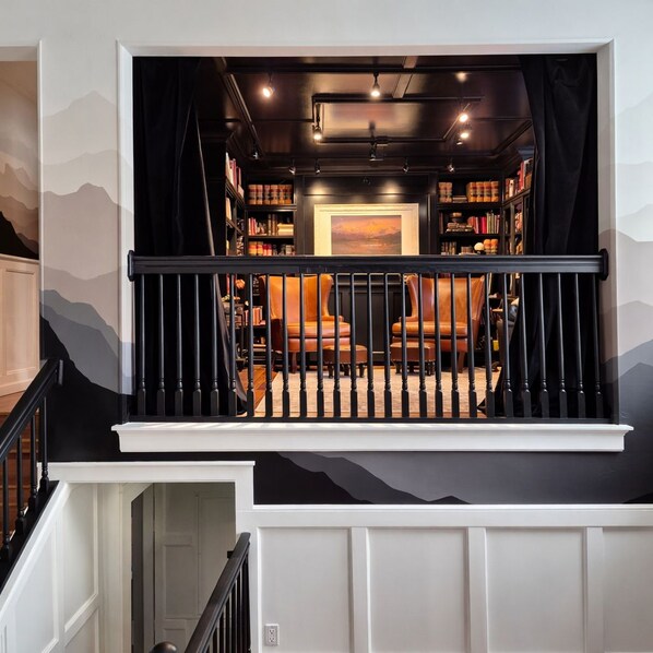 A staircase leading to a room with a bookshelf, a painting, and a chair.