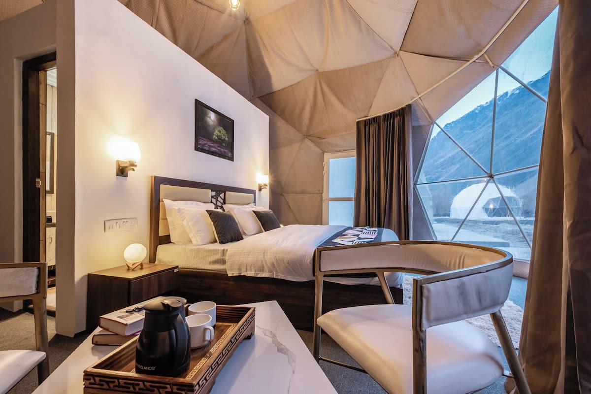 A cozy room with a bed, bedside table, and a view of a snowy landscape through a large window.