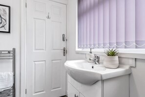A bathroom with a white sink, a towel rack, and a window with blinds.