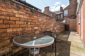 Un mur de briques, une table en verre et une chaise dans une cour.