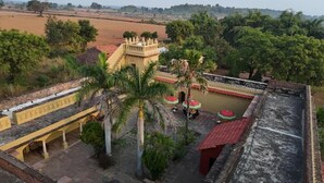 Un patio con fuente de agua, palmeras y un edificio de techo rojo.