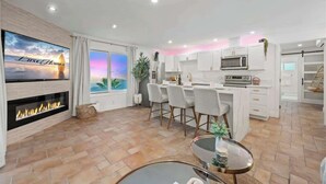 Una cocina moderna con armarios blancos, un microondas y una zona de comedor con sillas.