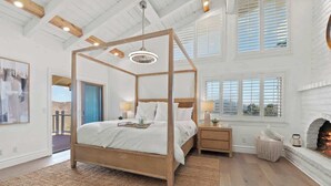 Un espacioso dormitorio con cama con dosel, chimenea y ventanas amplias.