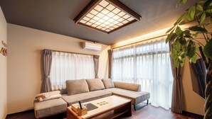 Una sala moderna con un sofá modular, una mesa de centro y un ventanal con cortinas traslúcidas.
