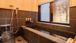 Un baño moderno con bañera, ducha y ventana con vistas a un árbol.