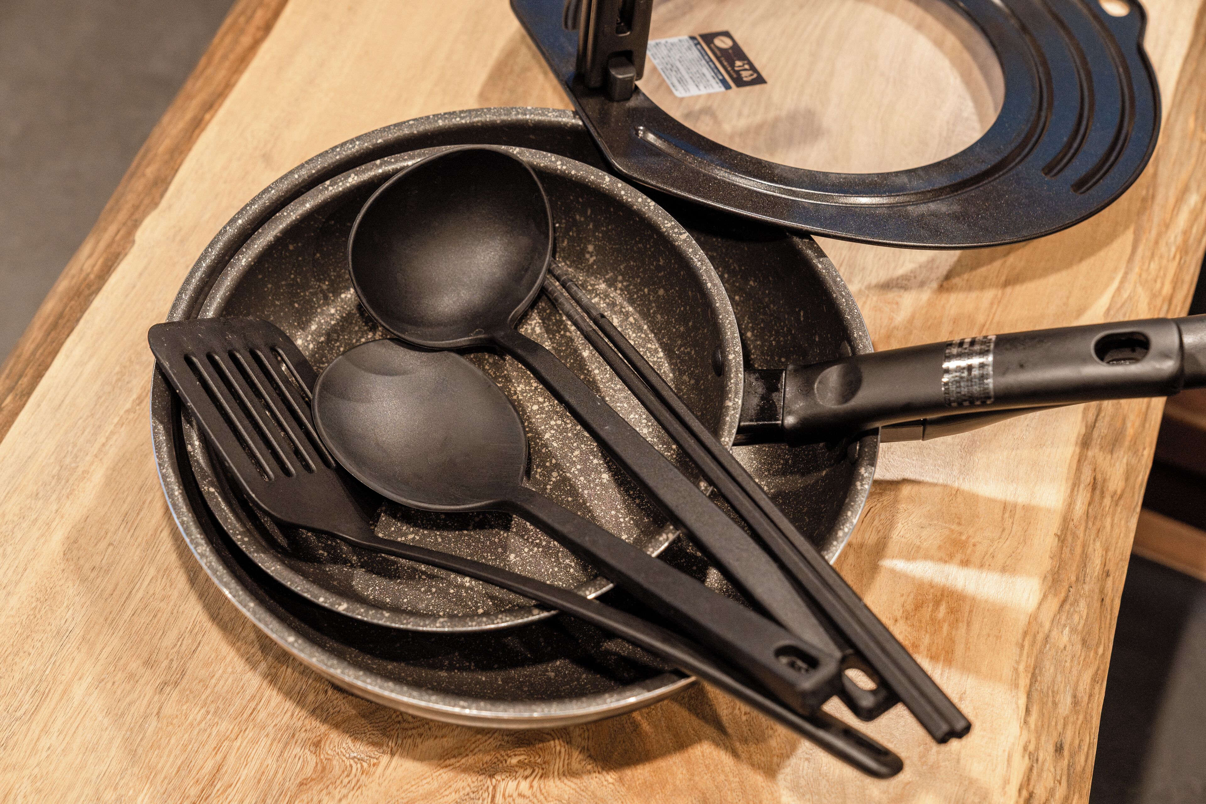A set of black kitchen utensils on a wooden table.