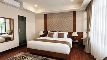 A hotel room with a large bed, bedside lamps, a mirror, a patterned wall, and a window with curtains.