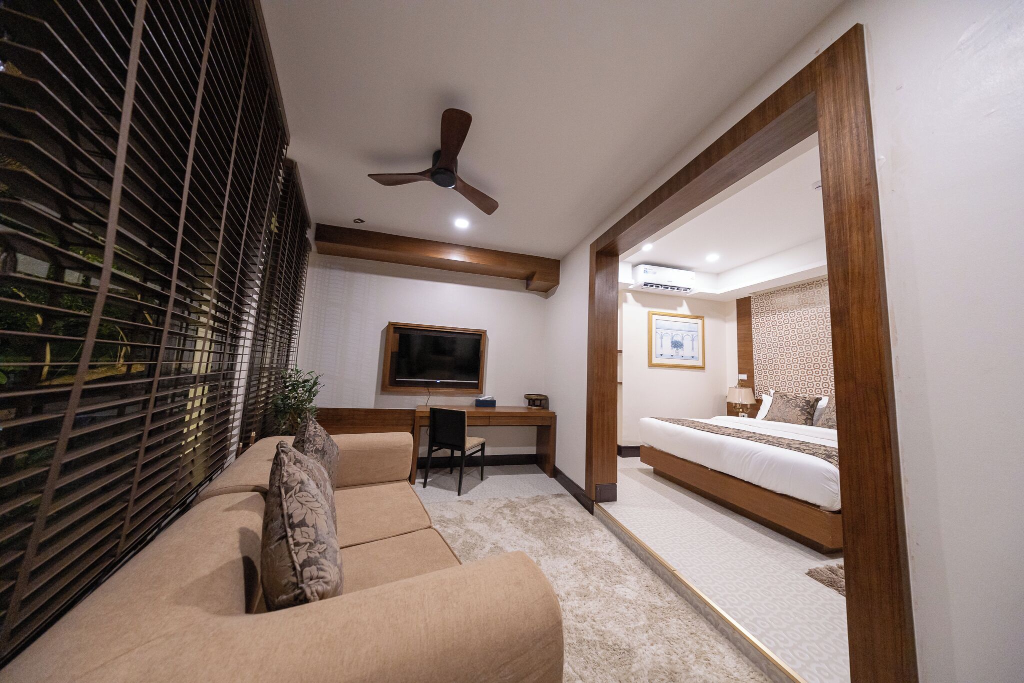 A modern bedroom with a bed, a desk, and a TV.