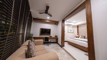 A modern bedroom with a bed, a desk, and a TV.