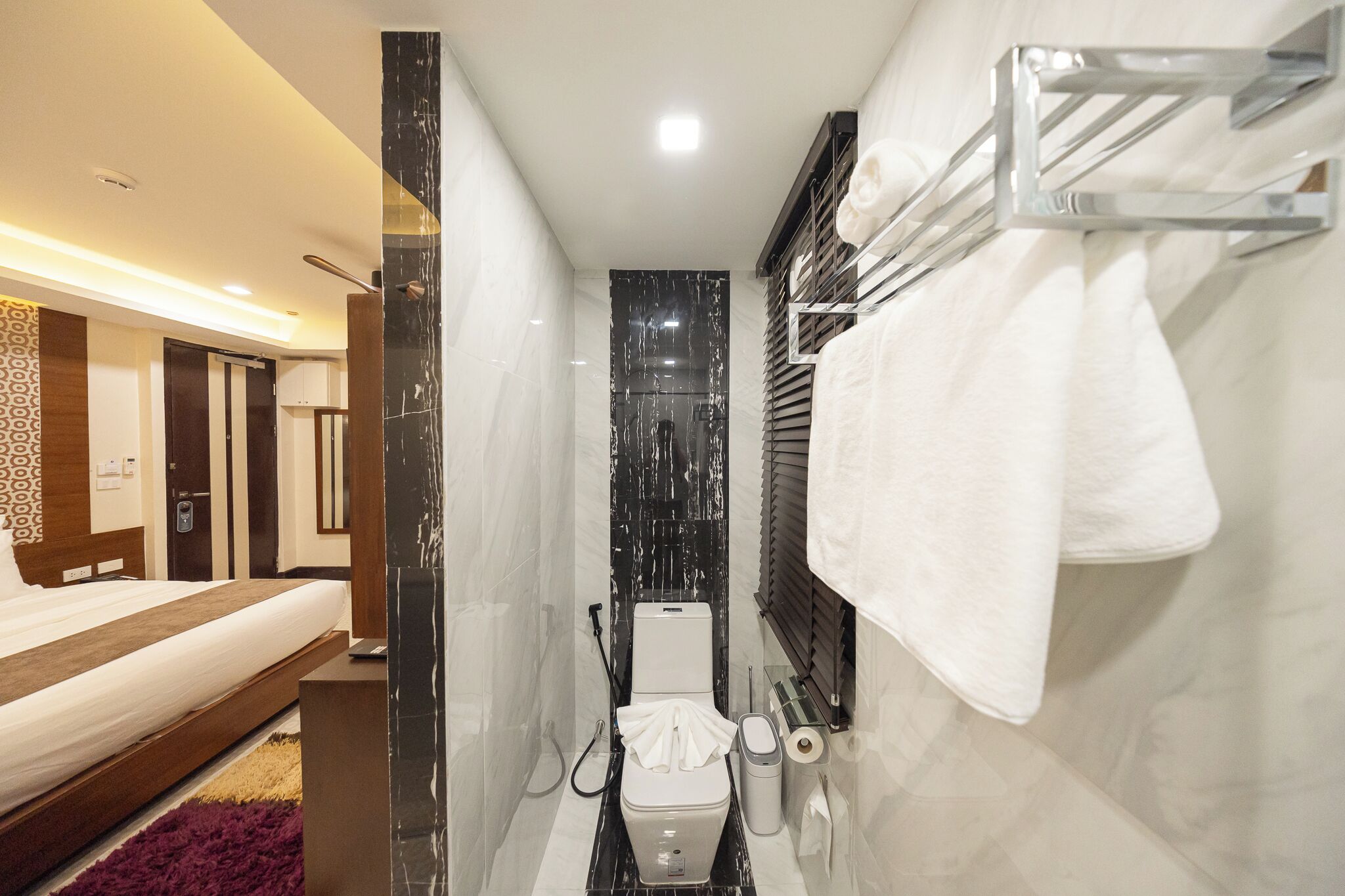 Un baño de hotel pequeño con ducha, inodoro y una mesita de noche.