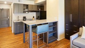 A compact kitchen with a bar stool, a coffee maker, and dark cabinets. - Cozy studio condo in Moab during Music Festival (Moab)