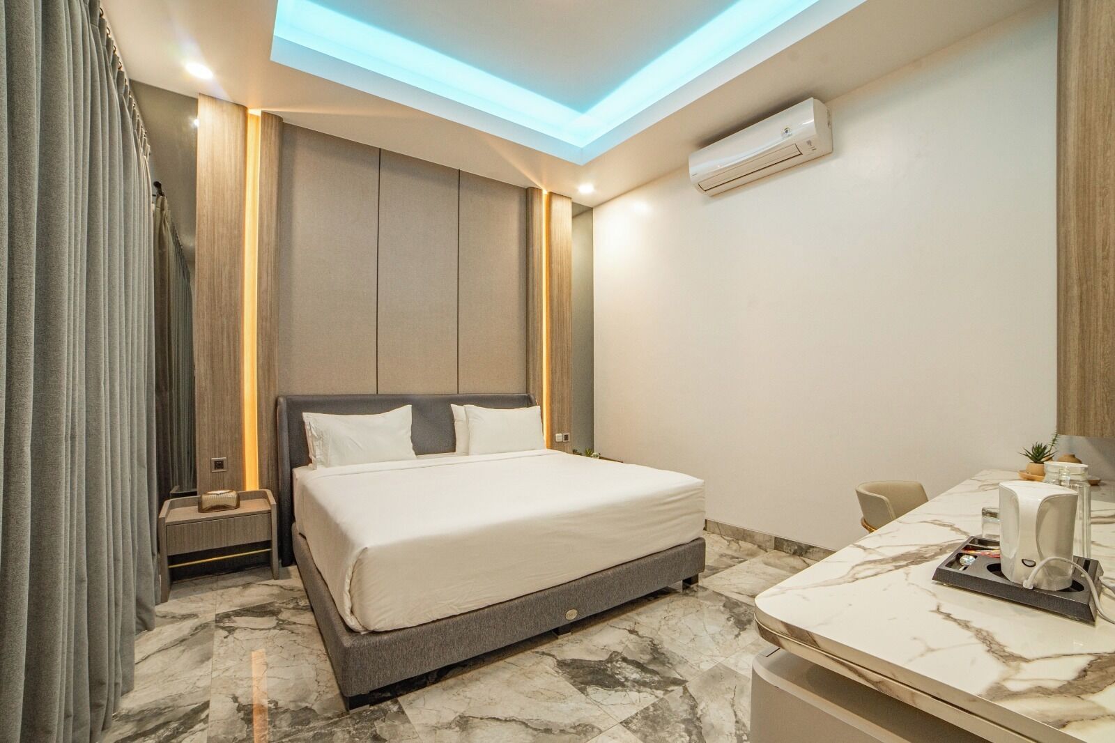 Une chambre d’hôtel moderne dotée d’un grand lit, d’un sol carrelé en marbre, d’une lucarne et d’un petit bureau avec une chaise.