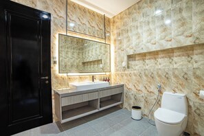 Un bagno moderno con schienale in marmo, uno specchio grande, un lavandino bianco e un water.