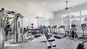 Une salle de sport équipée de machines de cardio, de matériel de musculation et d’haltères.