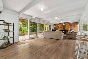 A spacious living room with a fireplace, wooden flooring, and a large sliding glass door leading to a balcony. - Buttercup cottage, Rye (Rye)