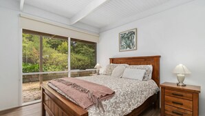 A bedroom with a large window, a wooden bed, a nightstand, and a framed picture on the wall. - Buttercup cottage, Rye (Rye)