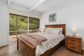 A bedroom with a large window, a wooden bed, a nightstand, and a framed picture on the wall. - Buttercup cottage, Rye (Rye)