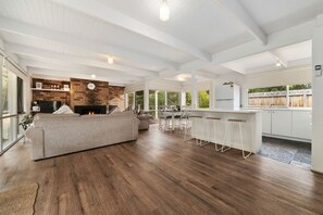A spacious living area with a large sofa, a fireplace, and a kitchen with a bar area. - Buttercup cottage, Rye (Rye)