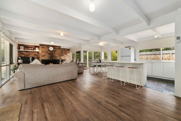 A spacious living area with a large sofa, a fireplace, and a kitchen with a bar area. - Buttercup cottage, Rye (Rye)