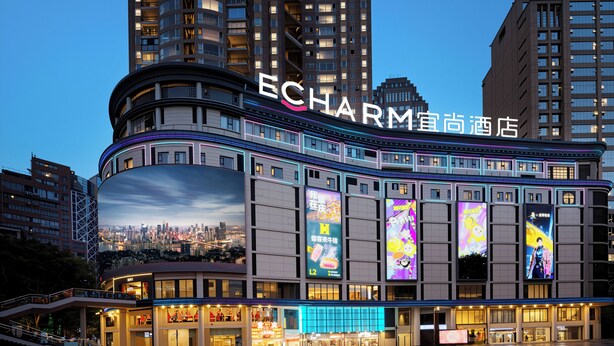 A hotel with a large curved facade, multiple balconies, and large digital billboards. - Echarm Hotel JiefangbeiPedestrianStreet  (Chongqing)