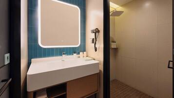 Une salle de bain moderne avec un lavabo blanc, un mur recouvert de carreaux bleus et une douche séparée par une paroi en verre.
