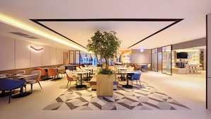 A modern hotel lobby with a central plant, multiple seating areas, and a kitchen visible in the background. - Echarm Hotel JiefangbeiPedestrianStreet  (Chongqing)