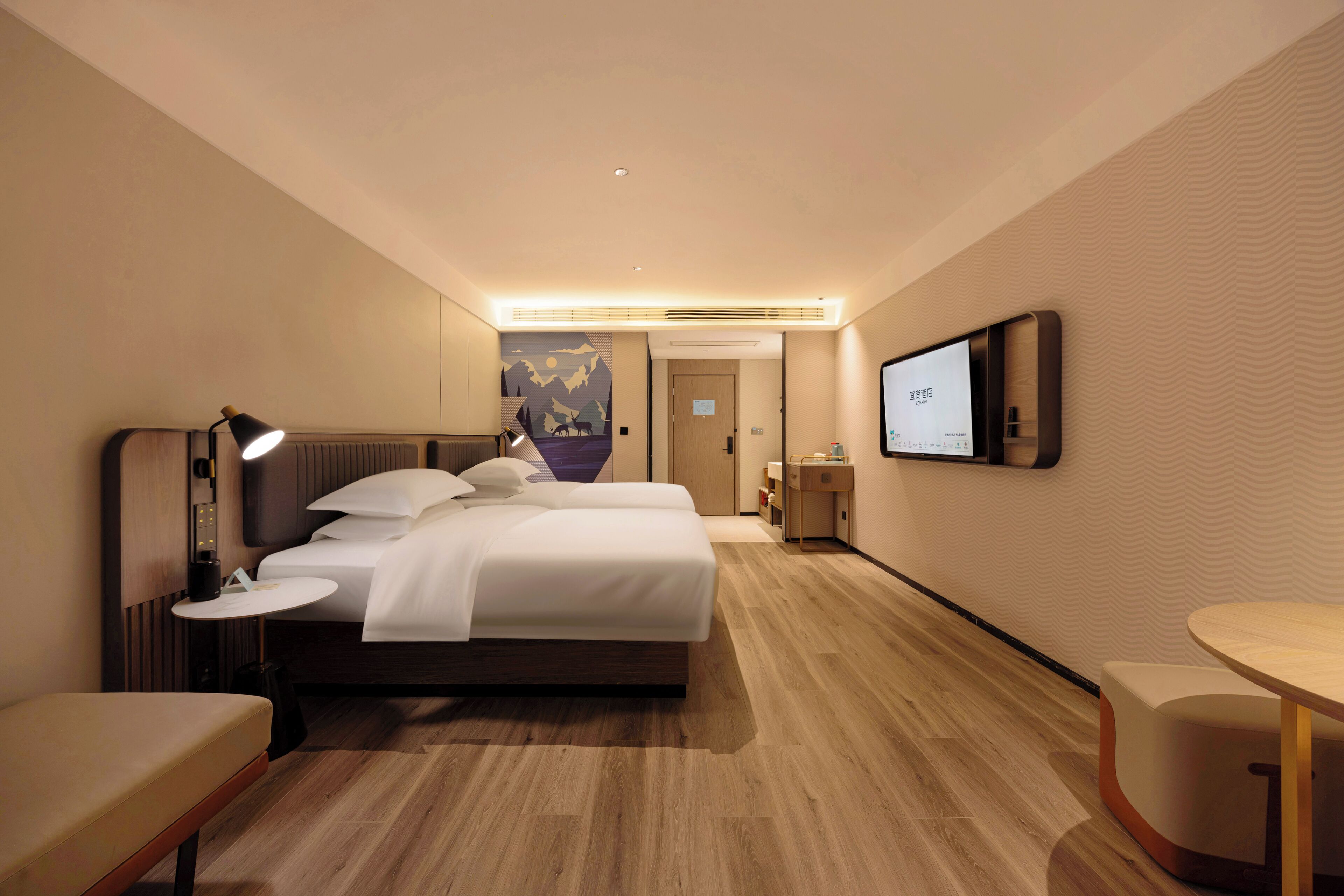 Una camera d'albergo moderna con un letto, un comodino, una lampada e una TV a parete.