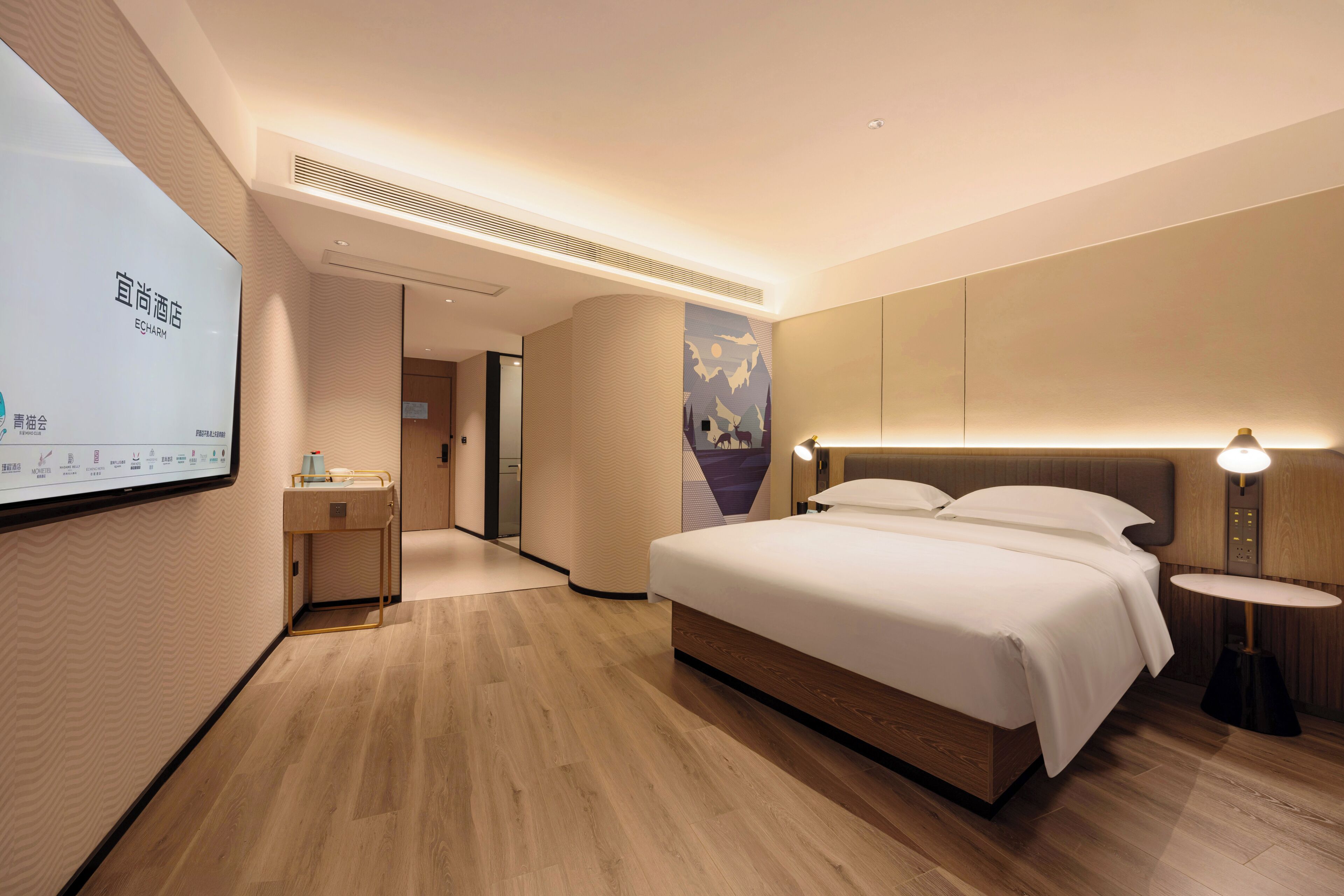 Ein modernes Hotelzimmer mit einem großen Bett, Nachttischen, einem Schreibtisch und einem an der Wand befestigten Fernseher.