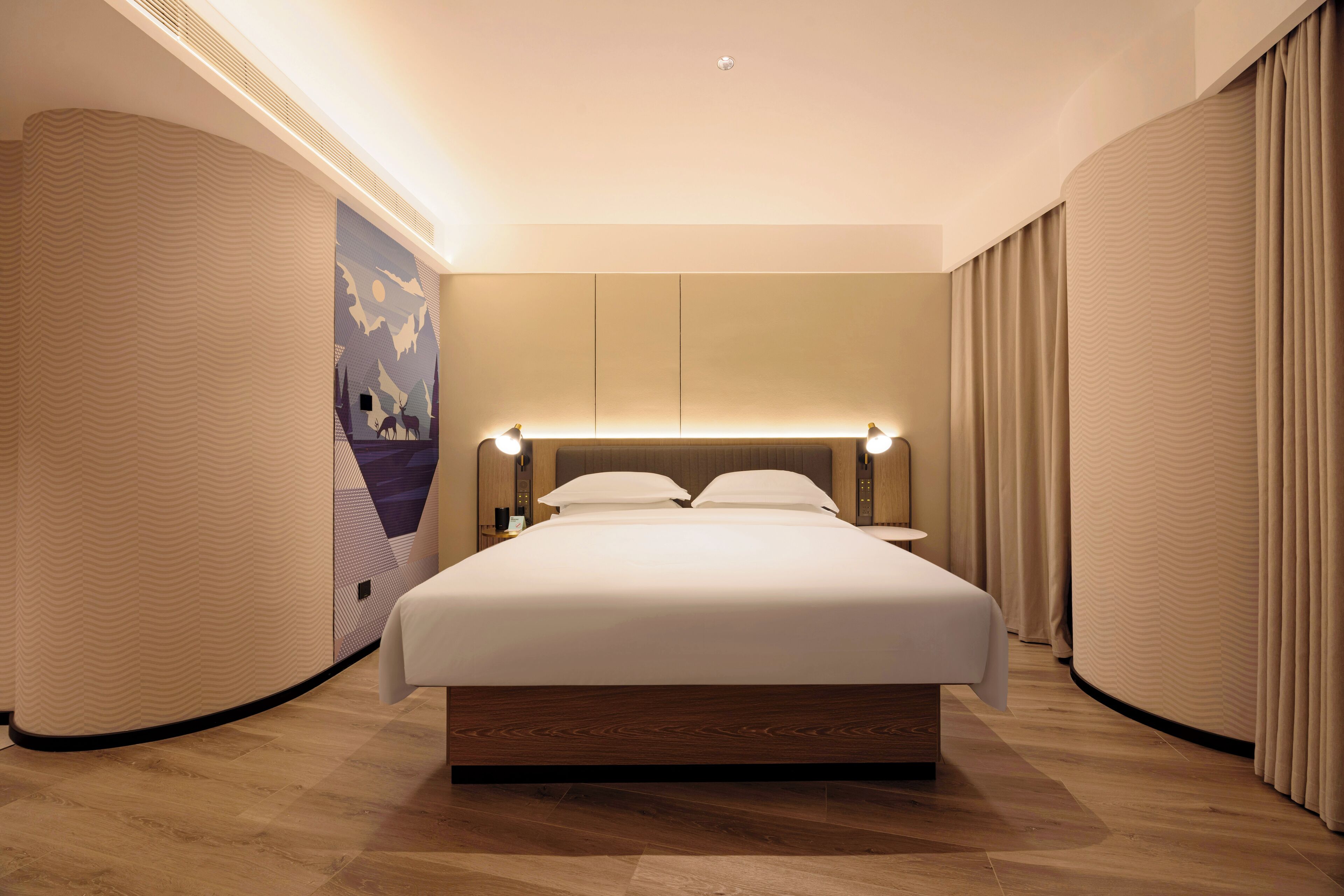A modern hotel room with a large bed, a headboard with integrated lighting, a wall mural, and a curved ceiling.